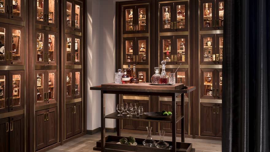 Bourbon cart in room with wood and glass display cases with liquor bottles 